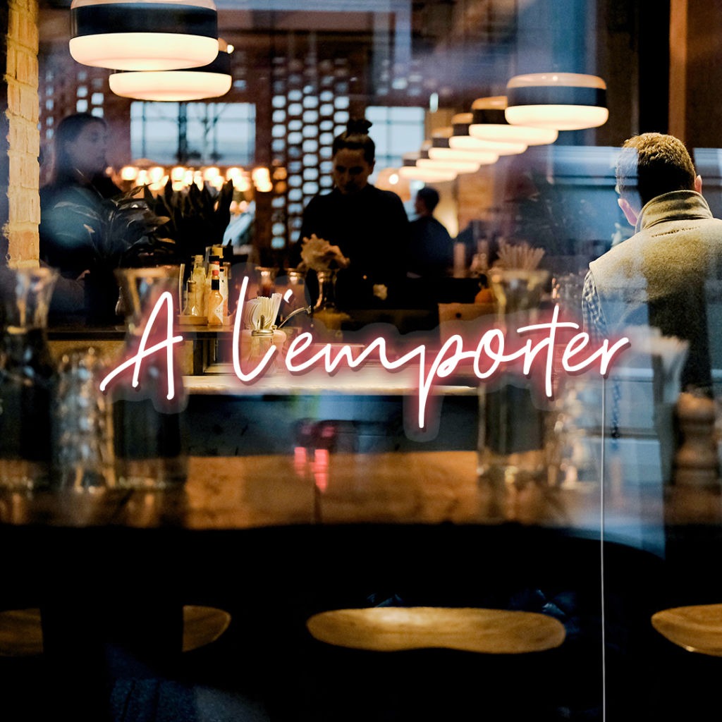 Néon LED « À l’emporter » sur une vitrine, devant la salle d’un bar