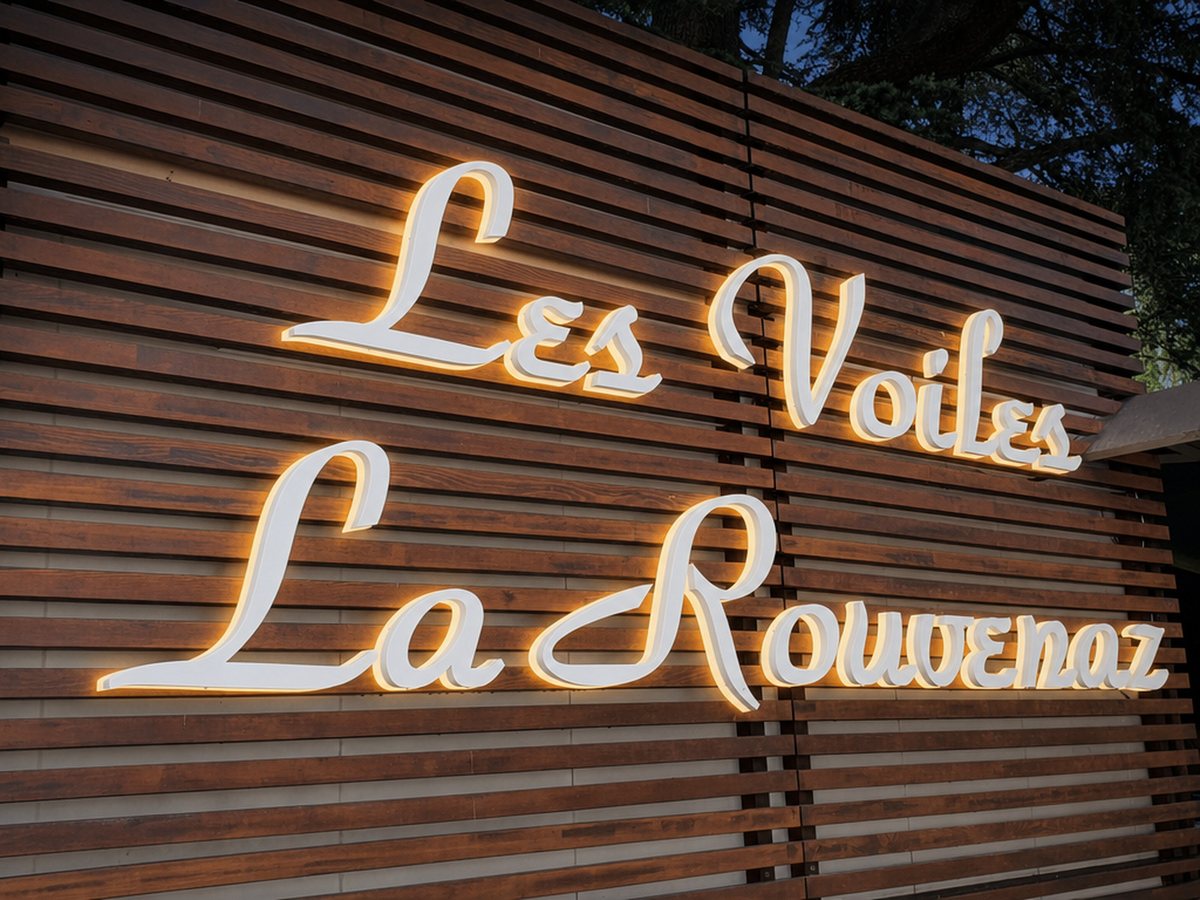 Lettres boîtier en relief posées par LED Studio sur un bardage bois, les deux lignes allumées en rétroéclairage