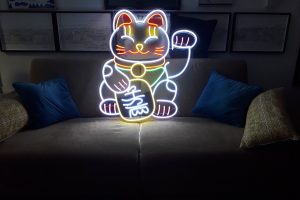 Néon Flex figurant un chat porte-bonheur multicolore, au-dessus d’un canapé