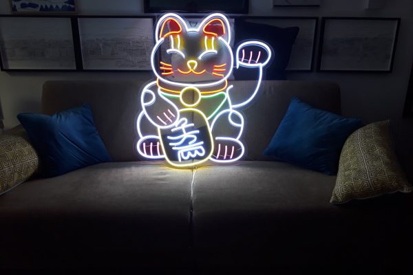 Néon Flex figurant un chat porte-bonheur multicolore, au-dessus d’un canapé